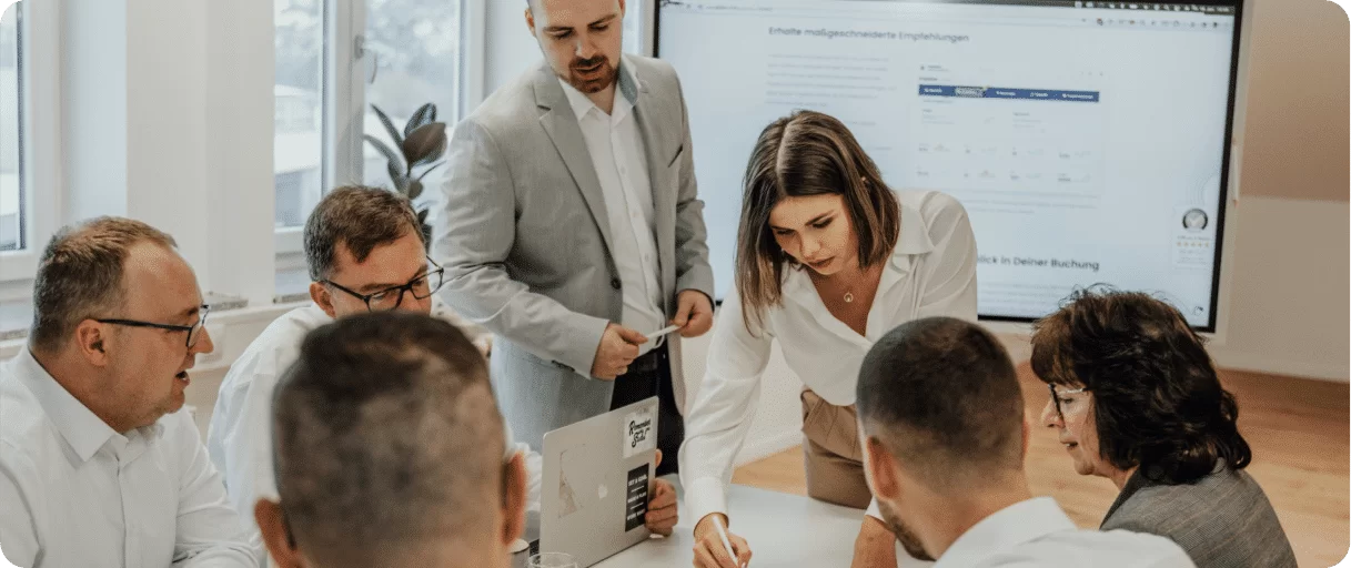 A business team of professionals in a boardroom discussing **frequently asked questions (FAQ)** and reviewing presentation material.